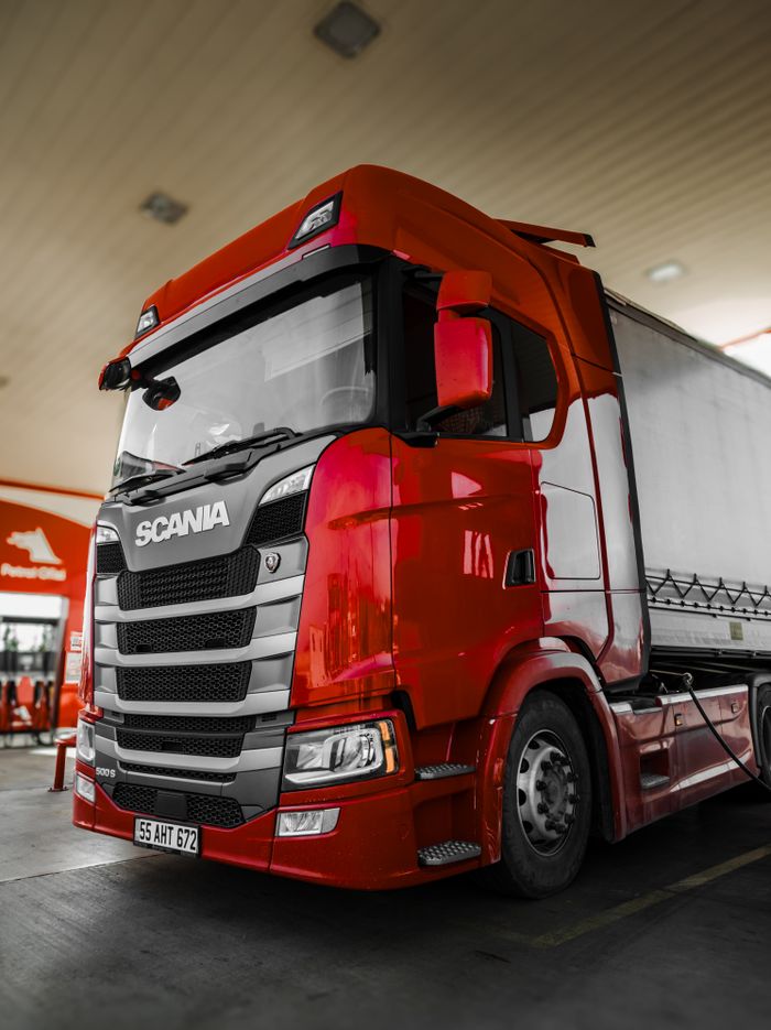 our-story-01 Bright red Scania truck parked at a fuel station with modern design and clean lines.