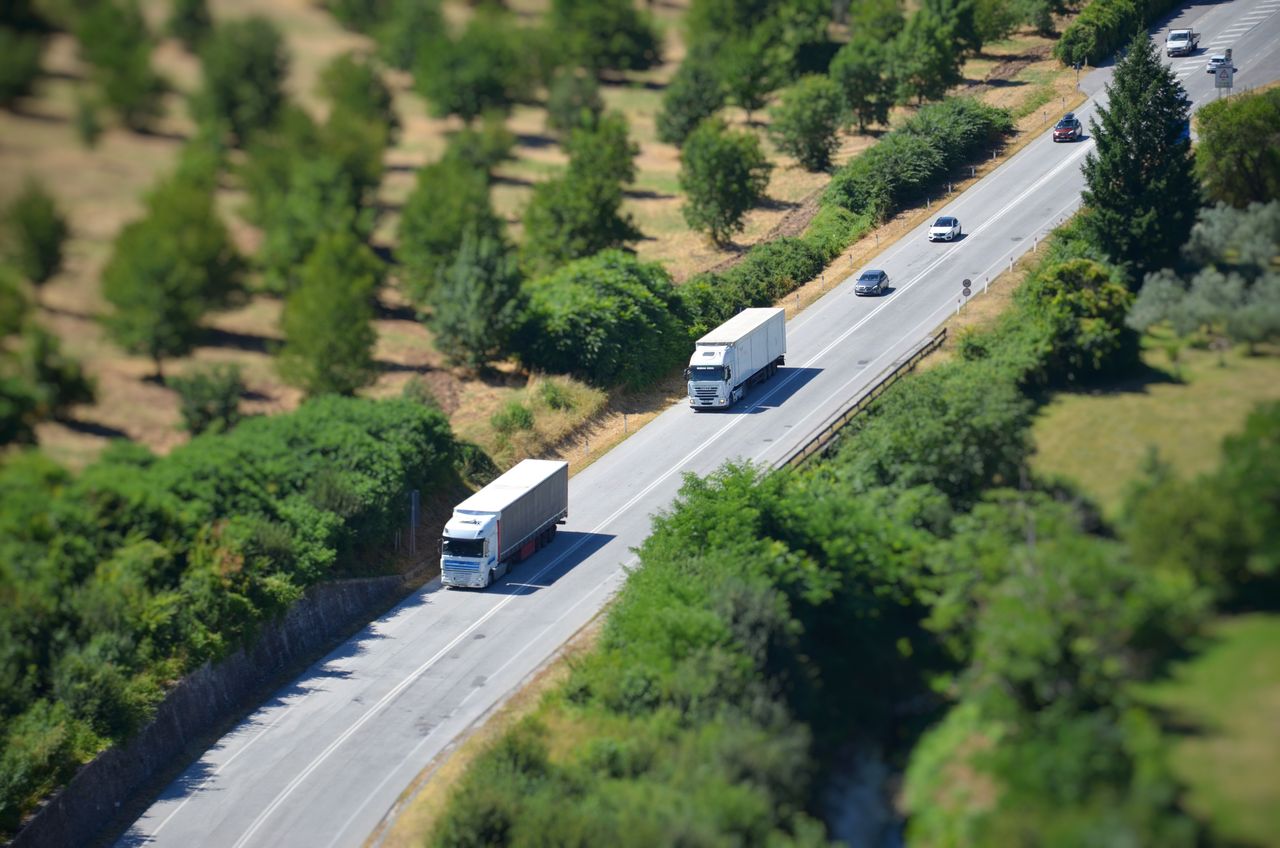 about-05 Aerial shot of a highway with trucks and cars surrounded by lush greenery.