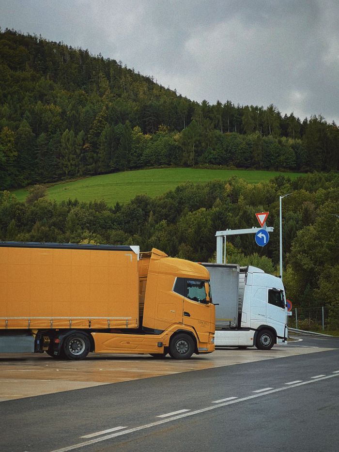 about-07 Yellow and white trucks parked at a scenic mountain rest stop under cloudy skies.
