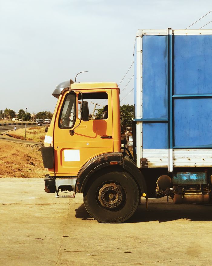 about-06 A colorful truck stands parked on a road in Nigeria, showcasing vibrant orange and blue colors.